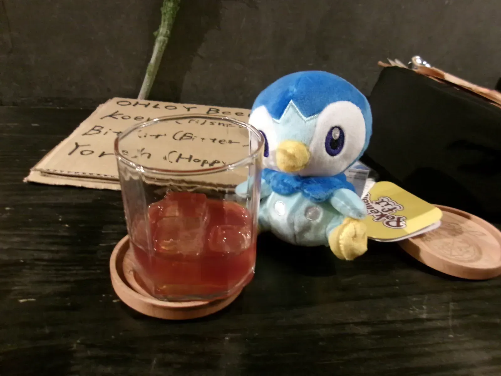A drink and small plush toy on a dark tabletop.