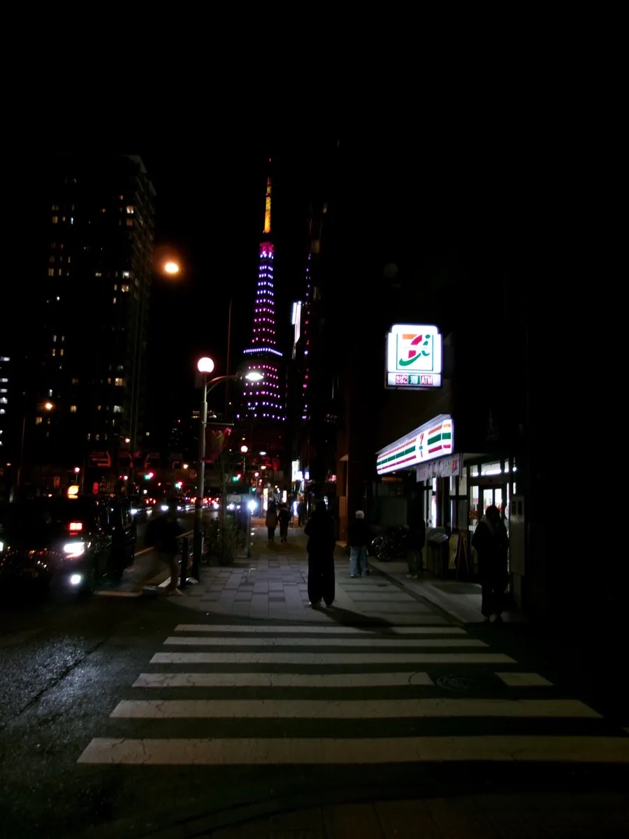 A Tokyo street at night with Tokyo Tower in the distance.